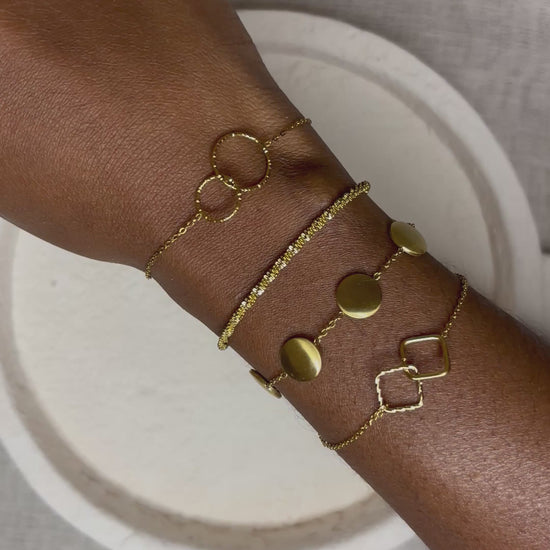 Bracelets dorés en acier inoxydable Gabriela portés au poignet - design minimaliste et élégant 